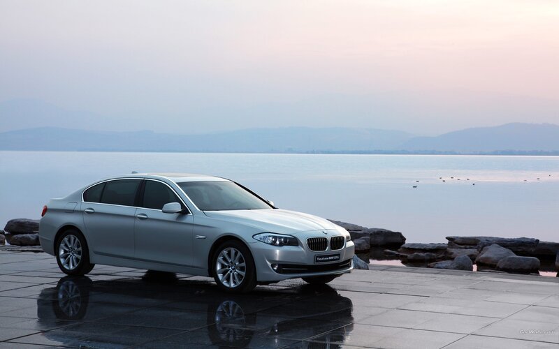 Silver BMW 5 Series by the lake