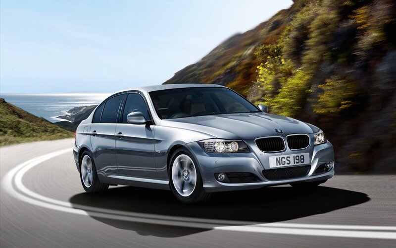 silver bmw driving on coastal road