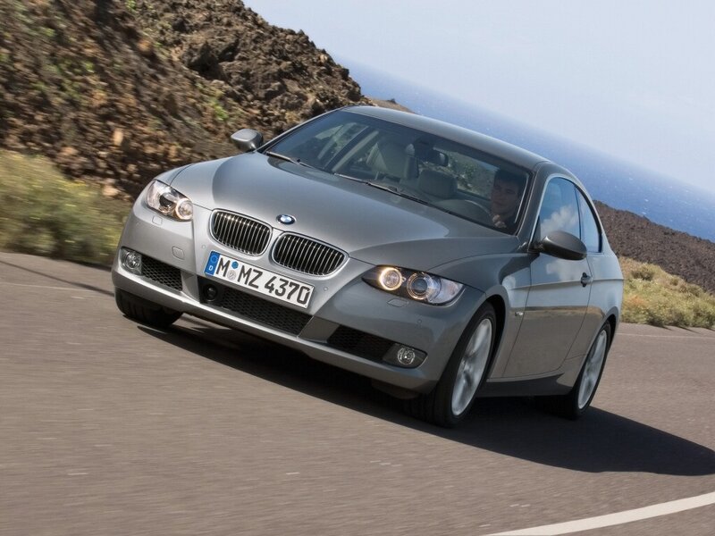 silver bmw driving on coastal road
