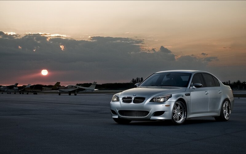 Silver BMW on tarmac at sunset