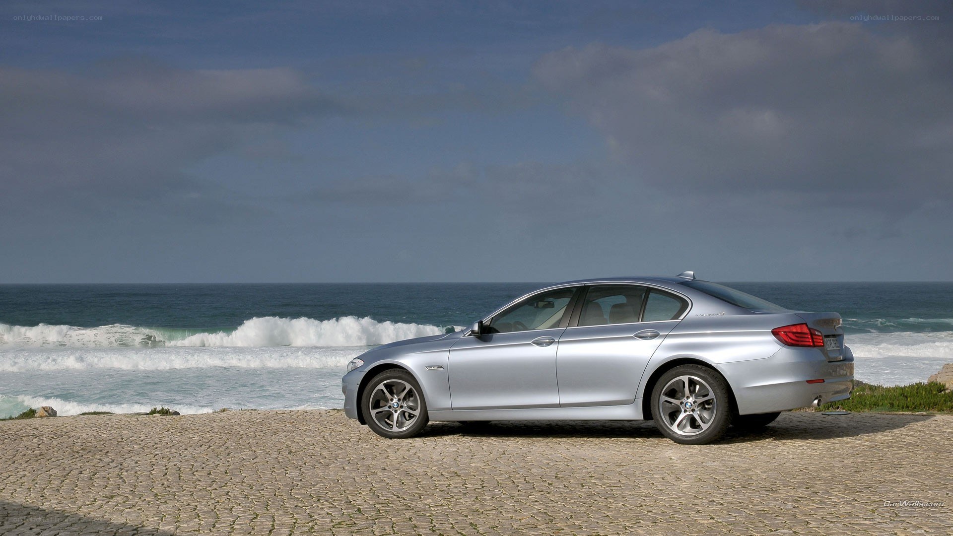 Silver BMW sedan by the ocean