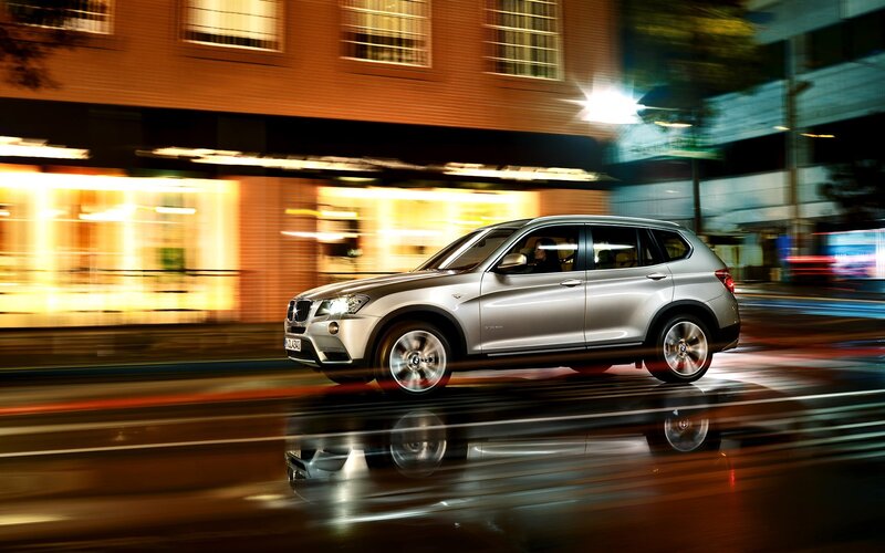 Silver BMW SUV in city at night
