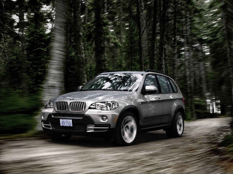 Silver BMW SUV on forest road
