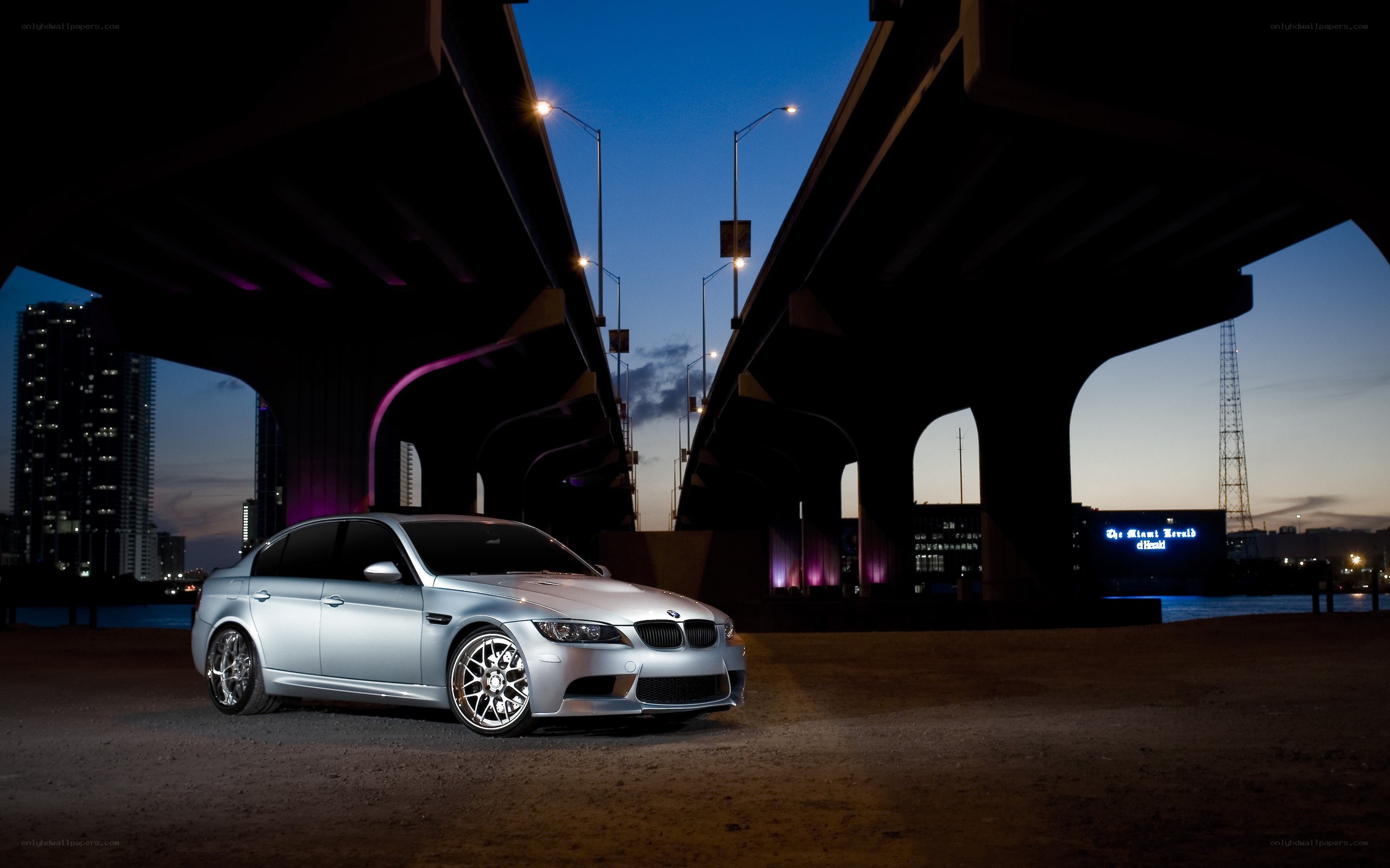 Silver BMW under a bridge at dusk