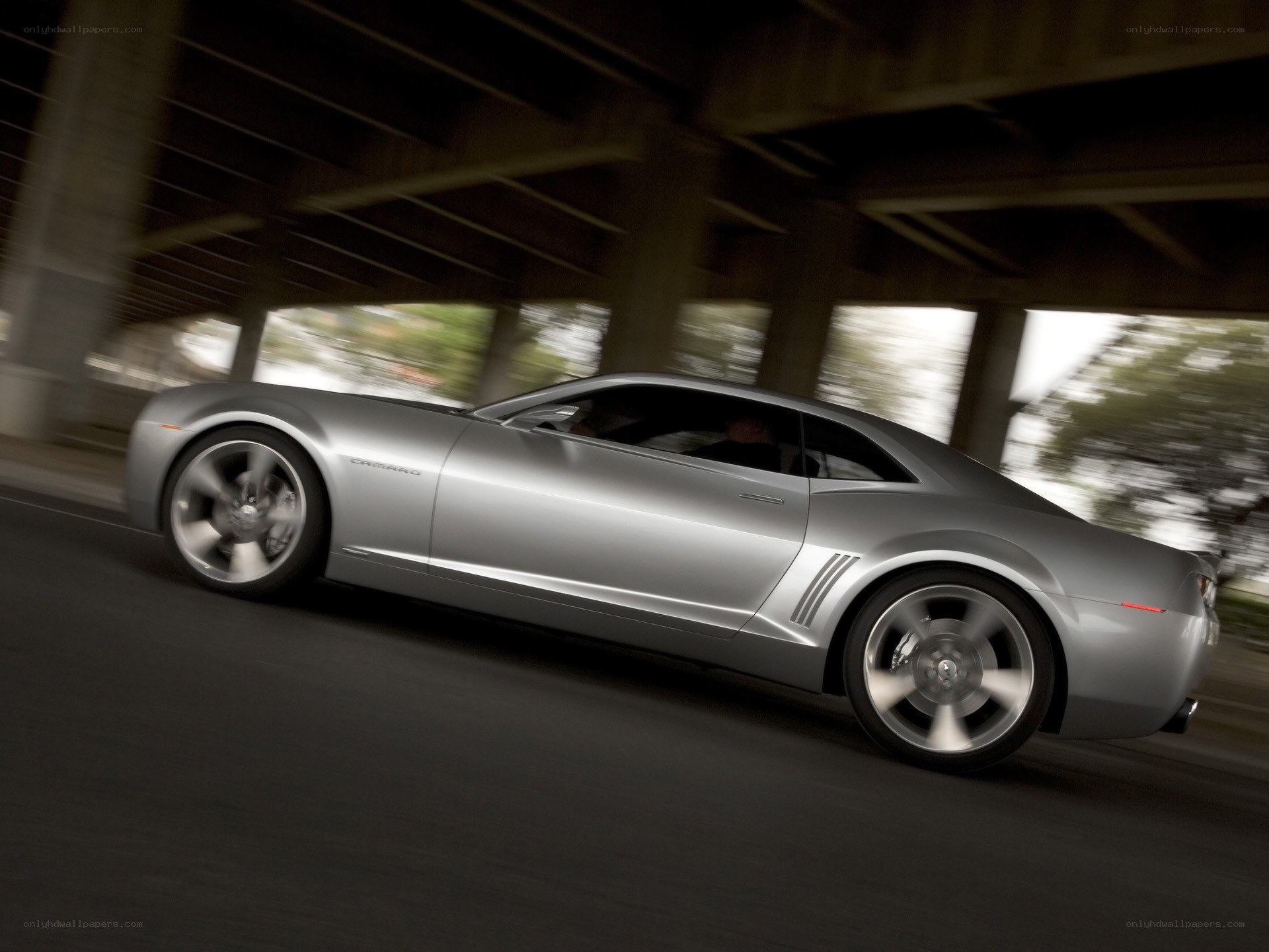 silver camaro driving under bridge