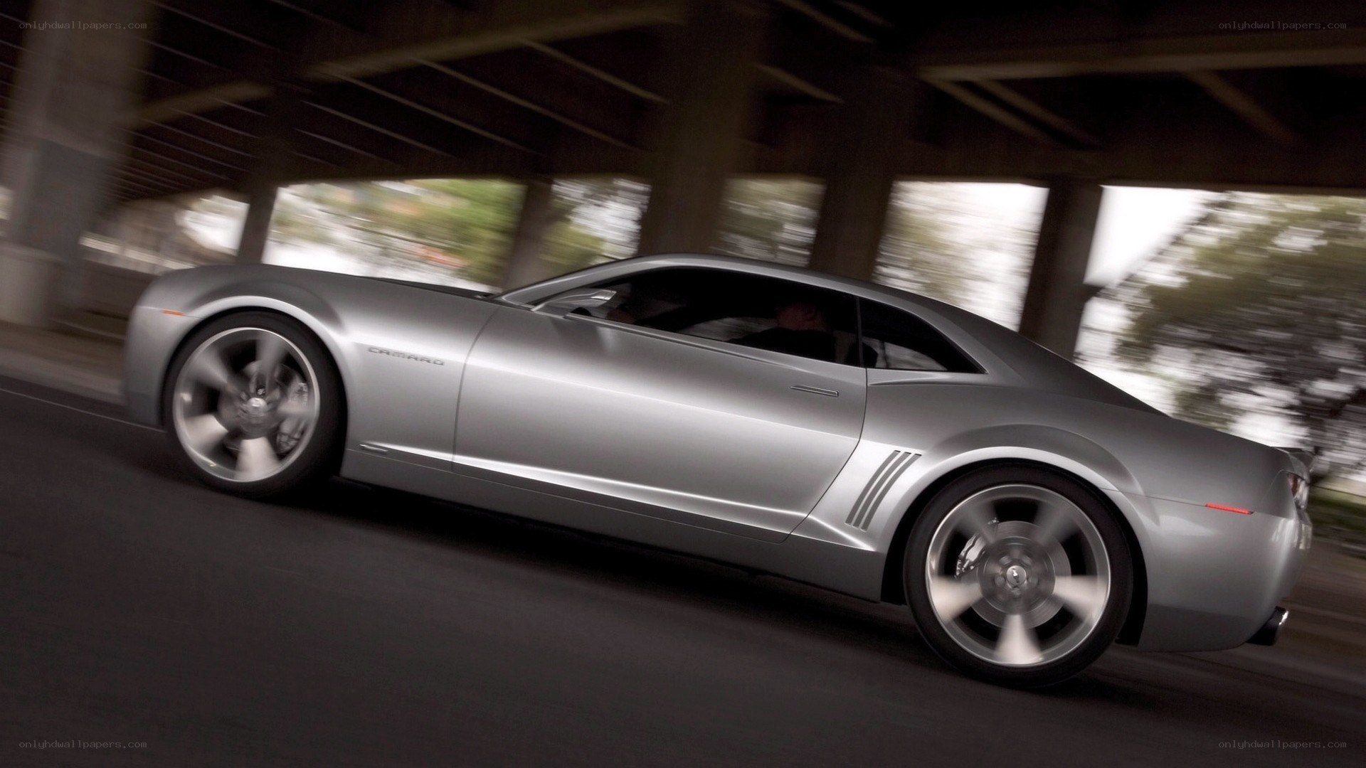 silver camaro driving under bridge