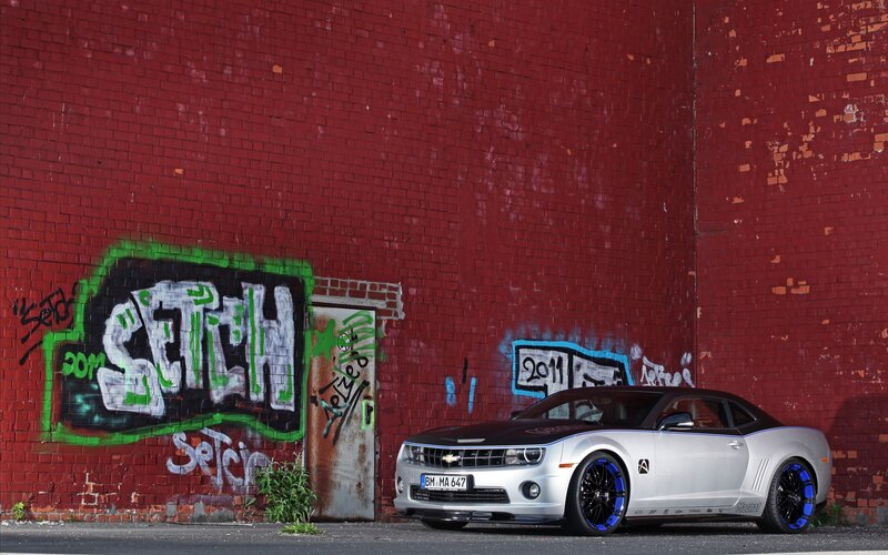 Silver Camaro in front of graffiti wall