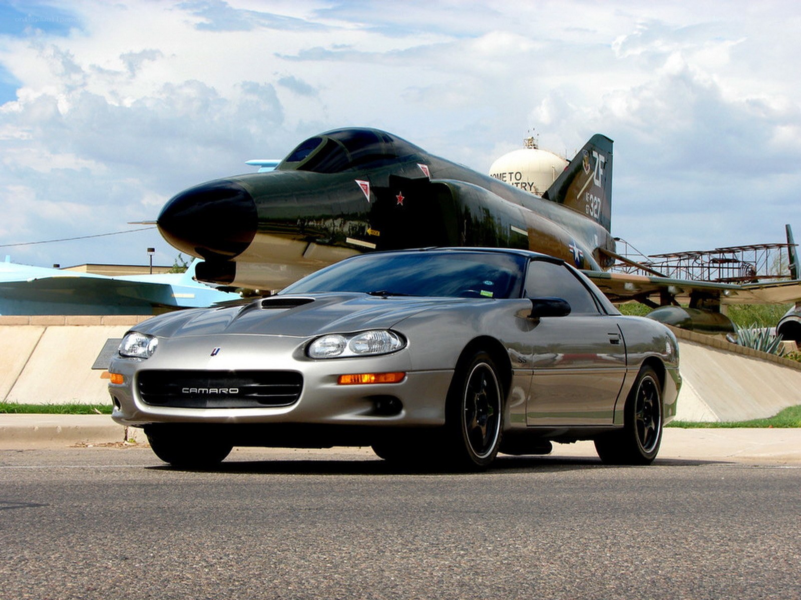 Silver Camaro with jet in background
