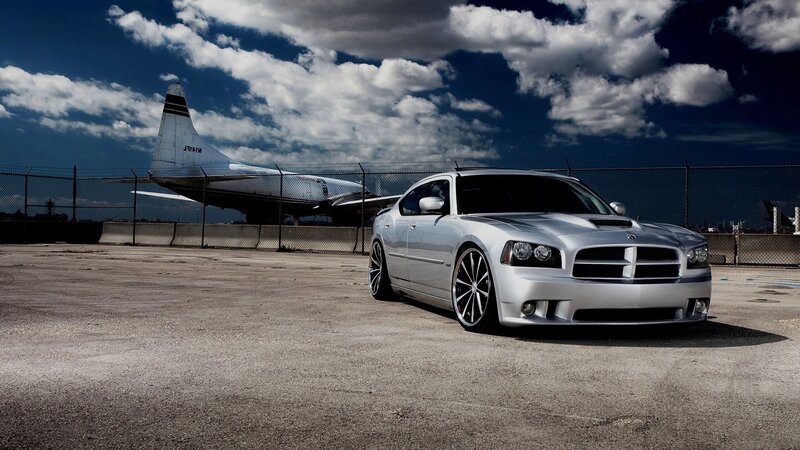 Silver car at airfield with plane