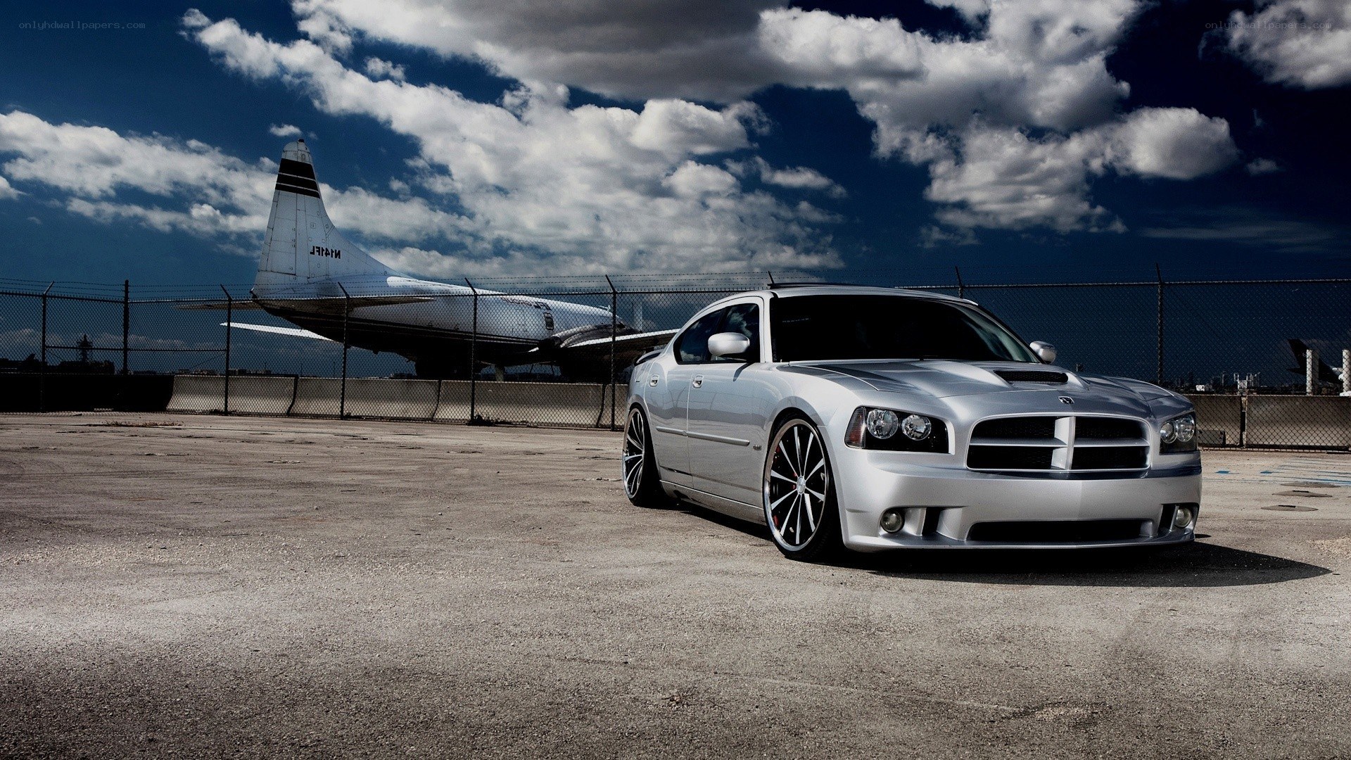 Silver car at airfield with plane