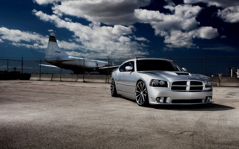 Silver car at airport with plane