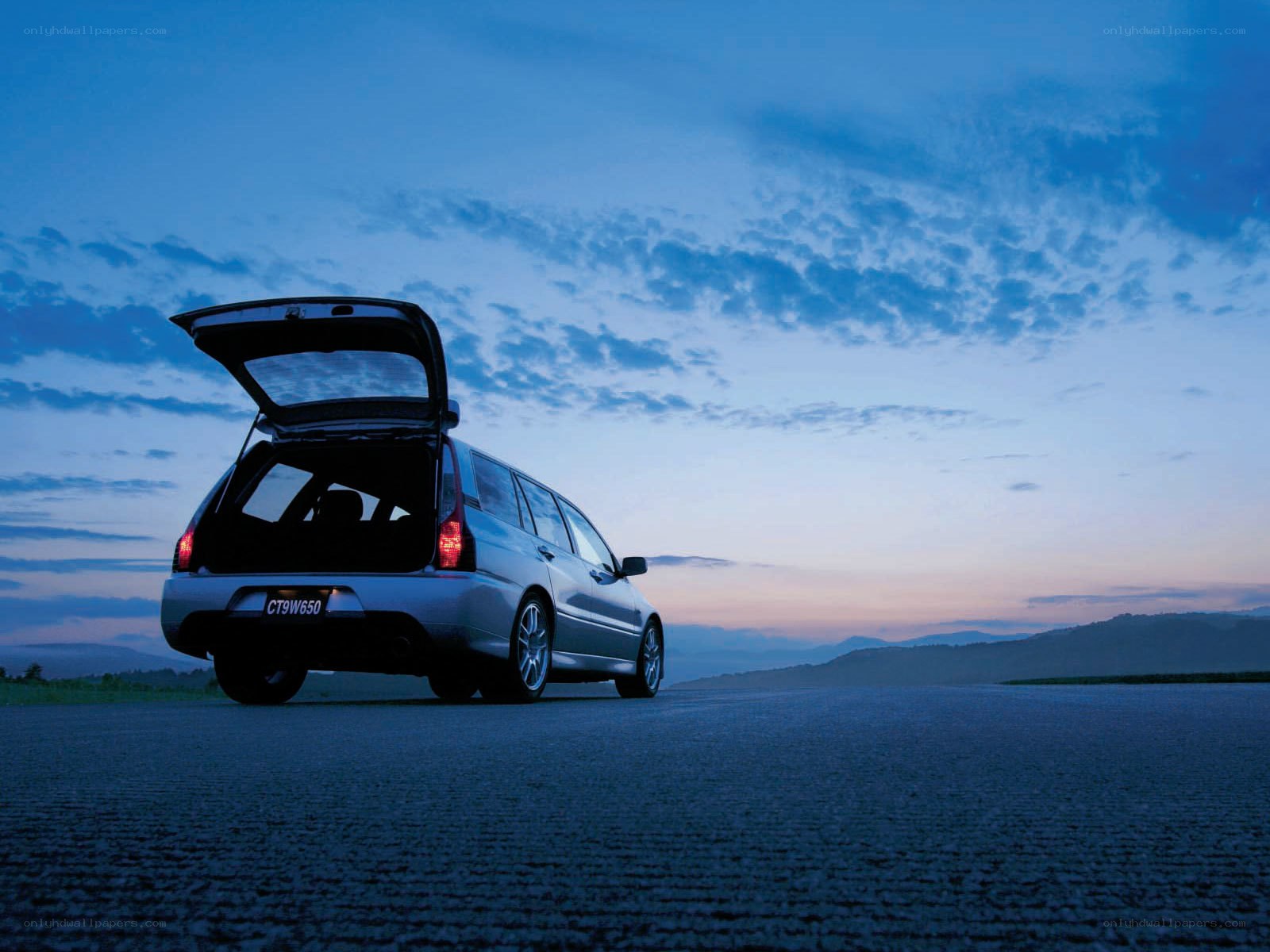 Silver car at dusk with open trunk