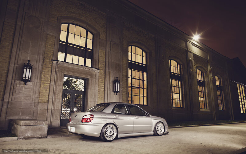 Silver car at night by building