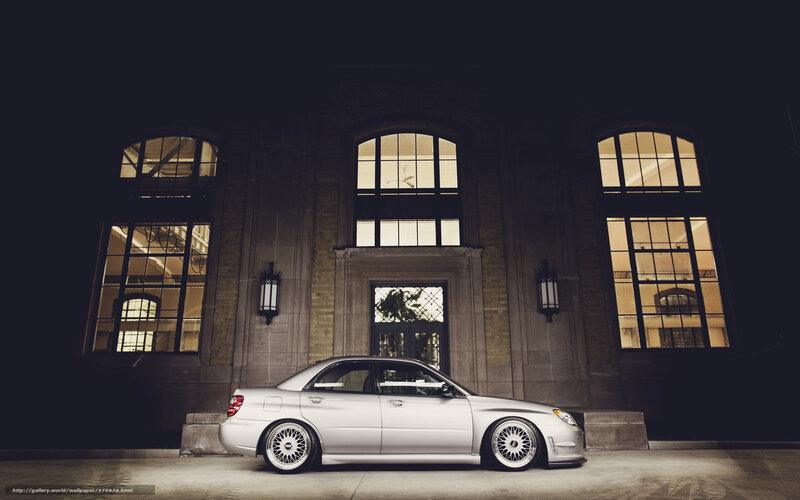 Silver car at night in front of building