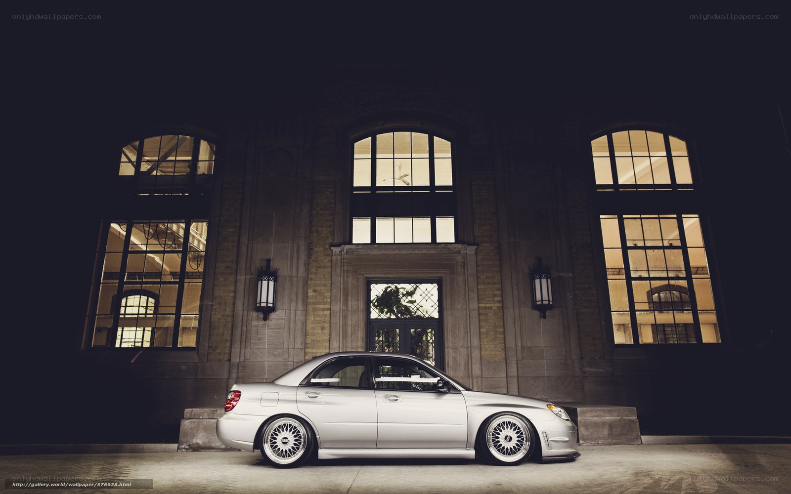 Silver car at night in front of building