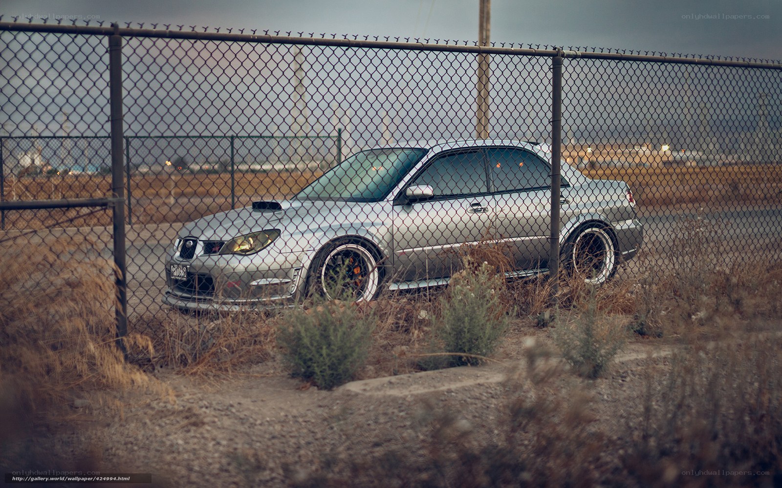 Silver car behind chain-link fence