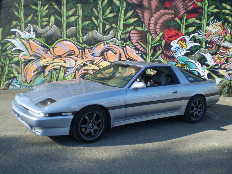 Silver car in front of graffiti wall