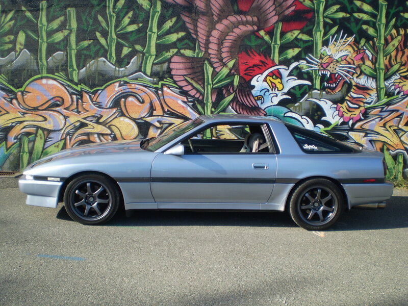 Silver car in front of graffiti wall