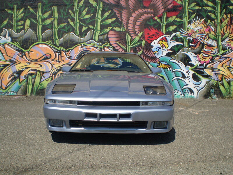 Silver car in front of graffiti wall