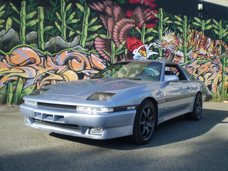 Silver car in front of graffiti wall