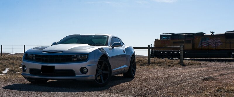 Silver car near train on dirt road