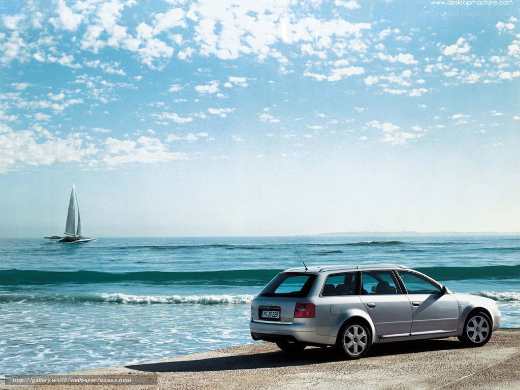 Silver car on beach with sailboat