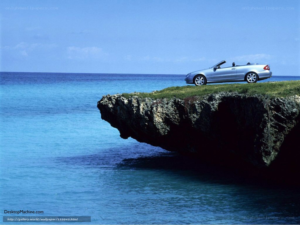 Silver car on cliff overlooking ocean