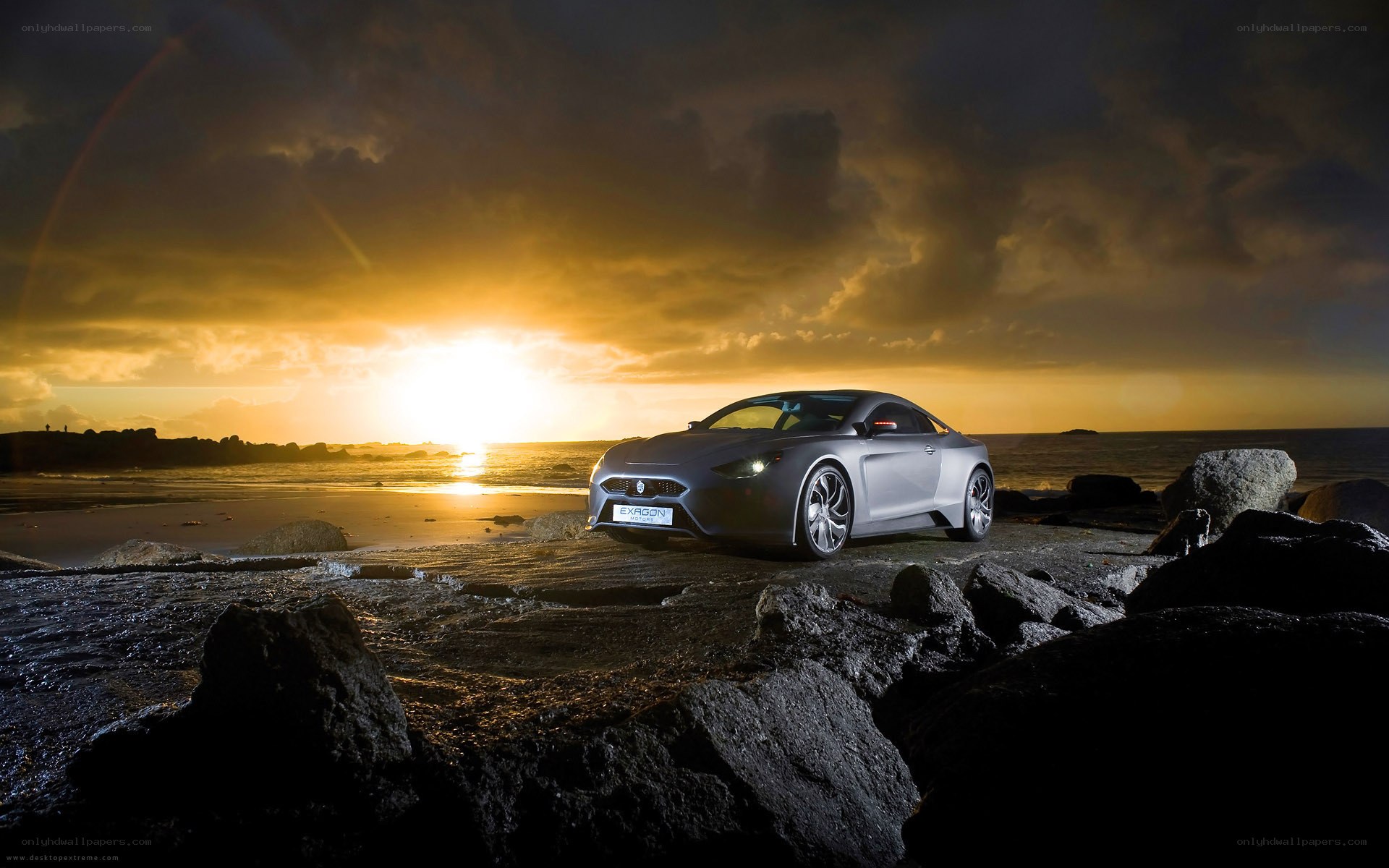 Silver car on rocky beach at sunset