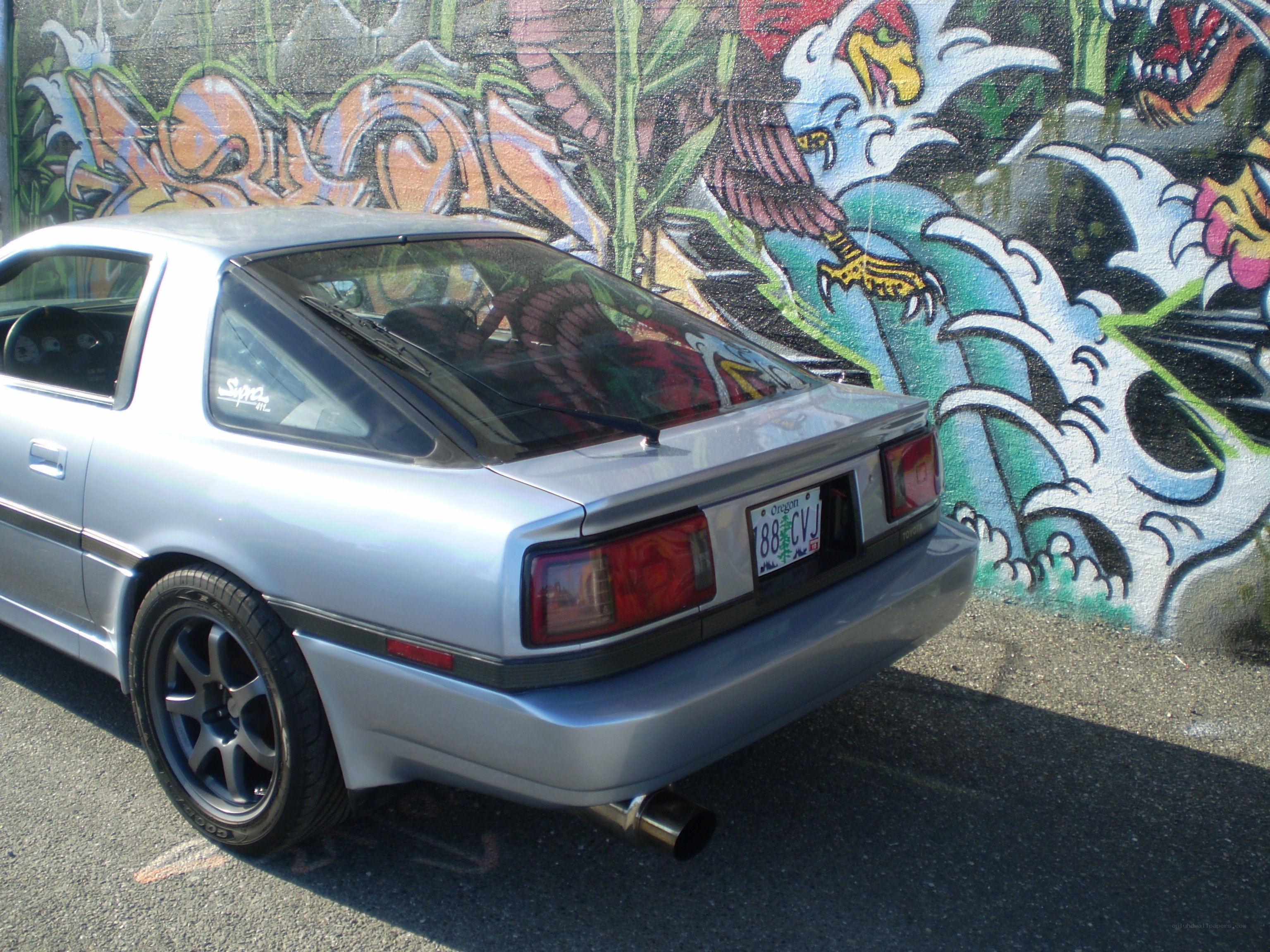 Silver car parked by graffiti wall