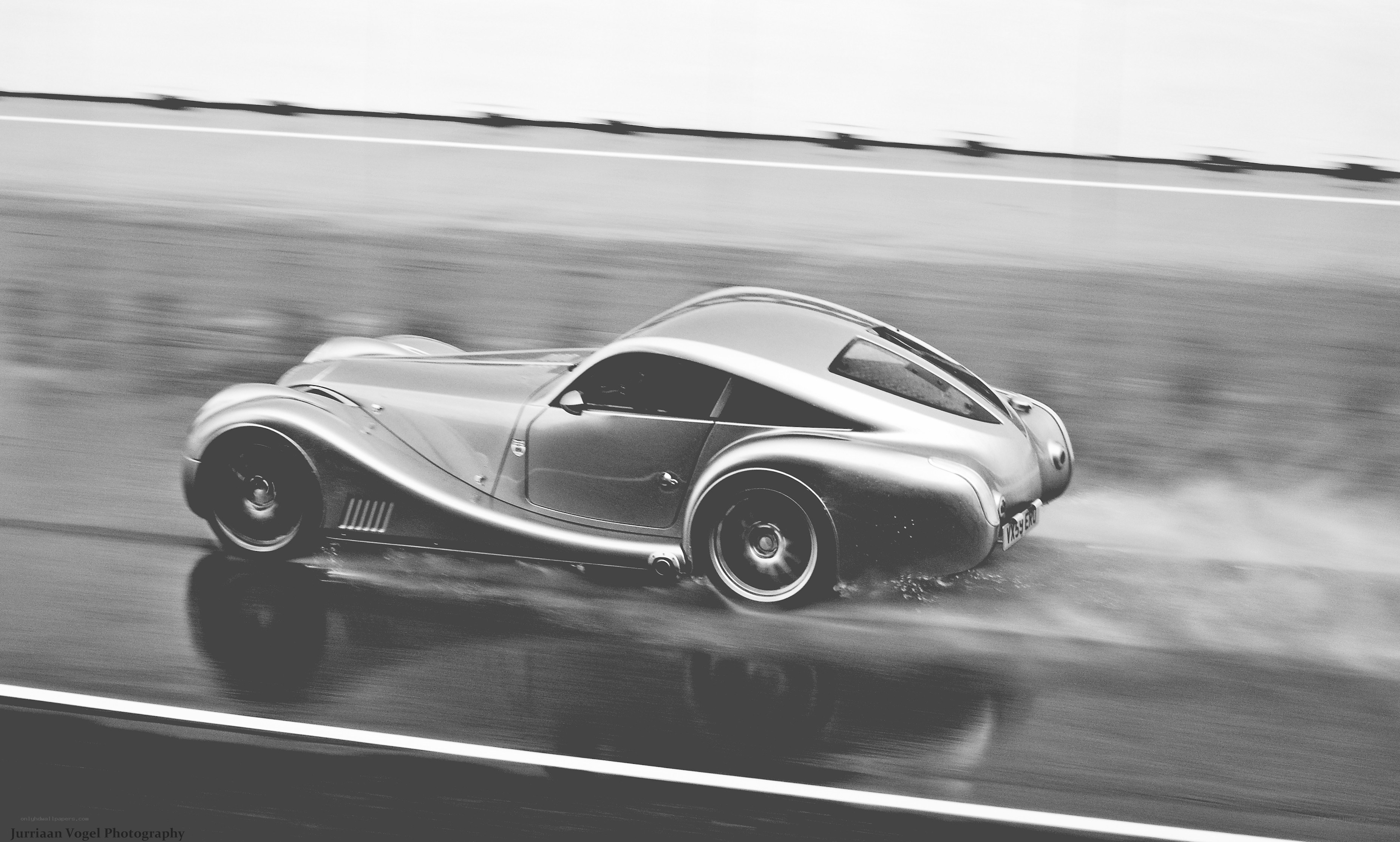 Silver car racing on wet track
