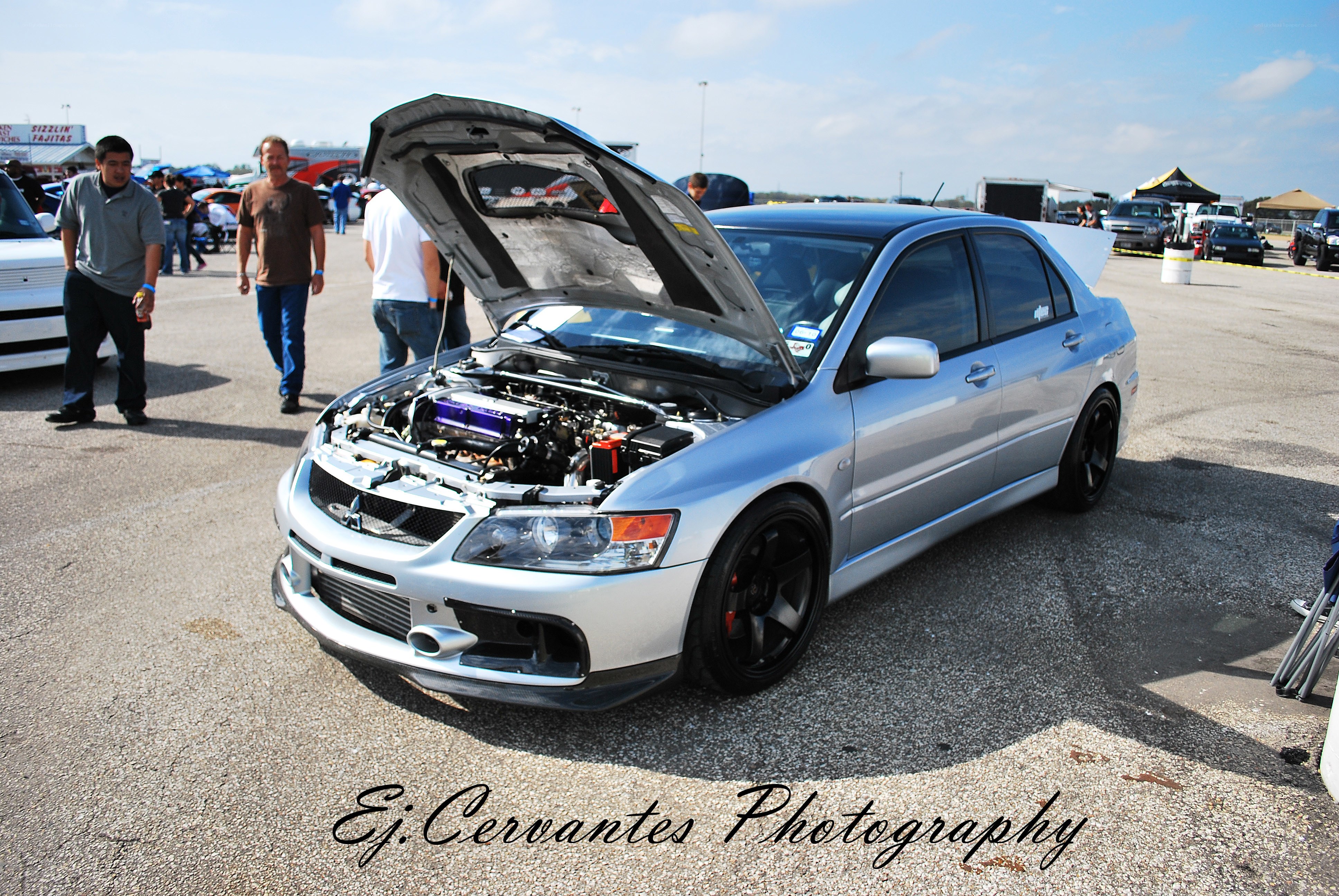 Silver car with open hood at event