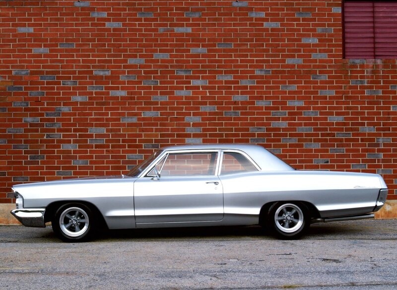 Silver classic car against brick wall
