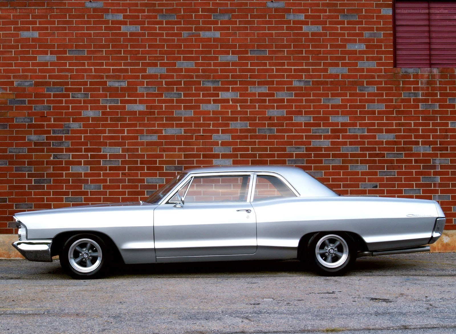 Silver classic car against brick wall