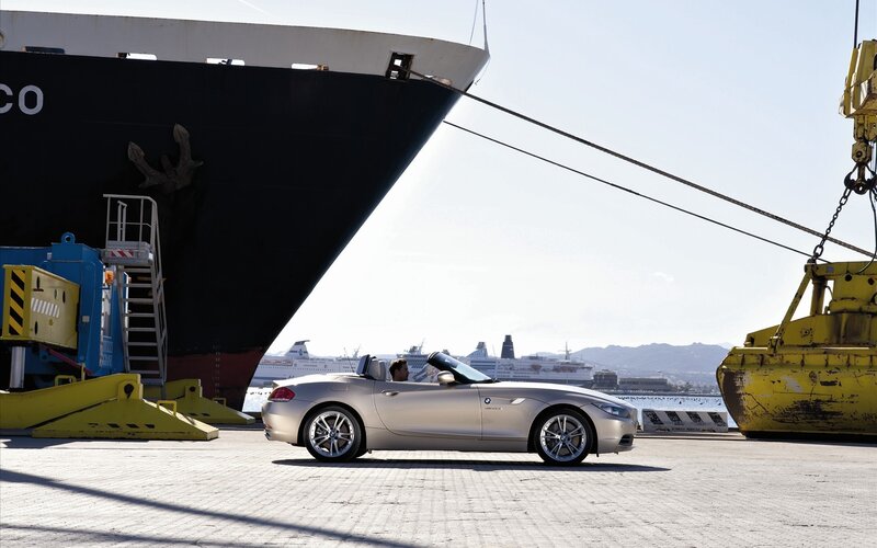 Silver convertible by a ship