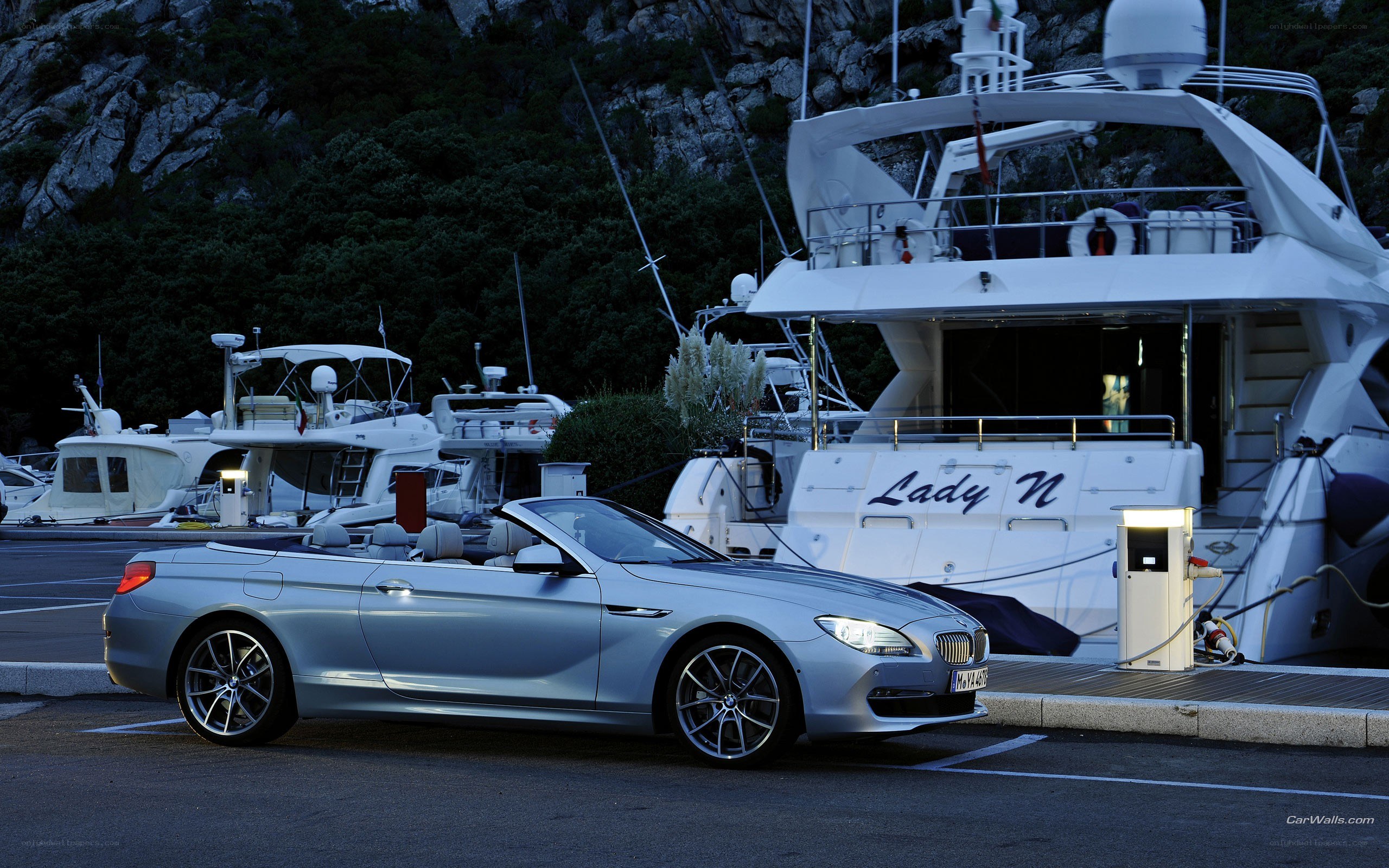 Silver convertible by a yacht