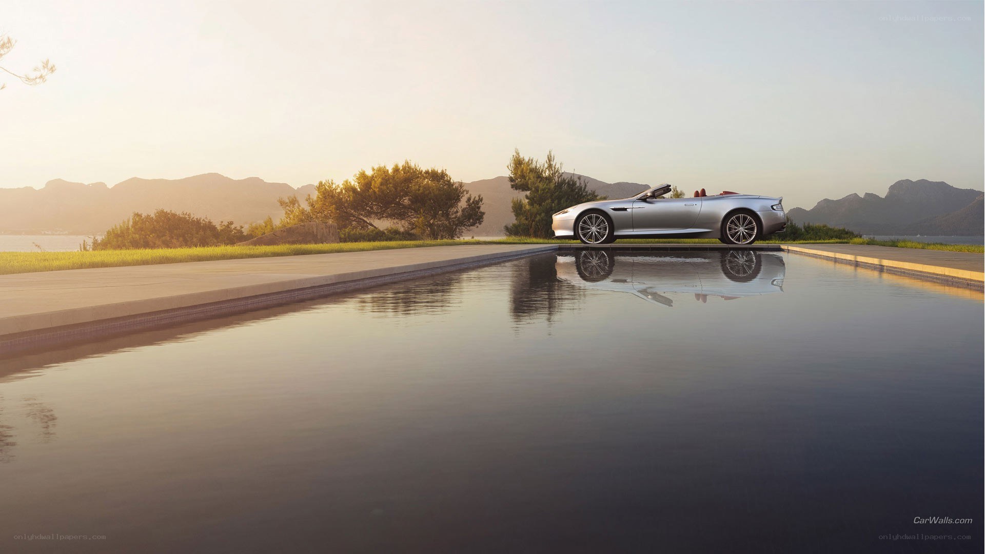 Silver convertible by pool at sunset
