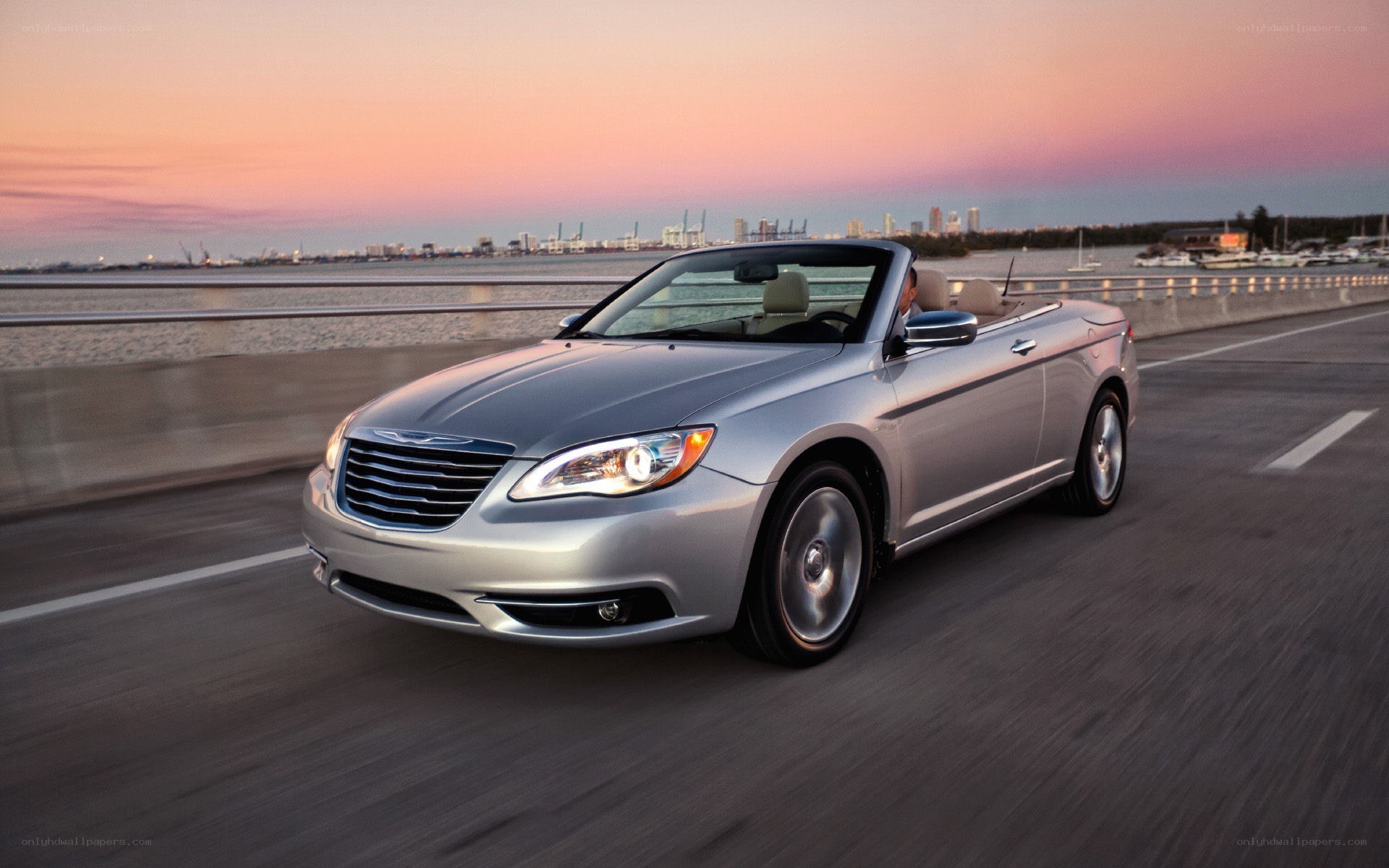 Silver convertible driving at sunset