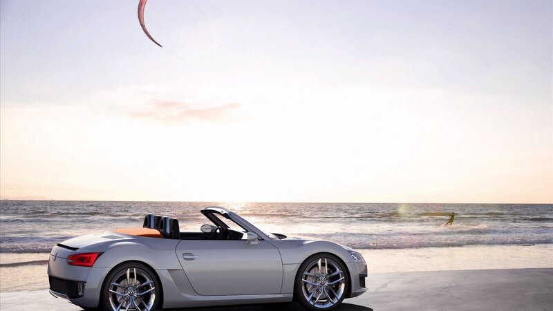 Silver convertible on beach at sunset