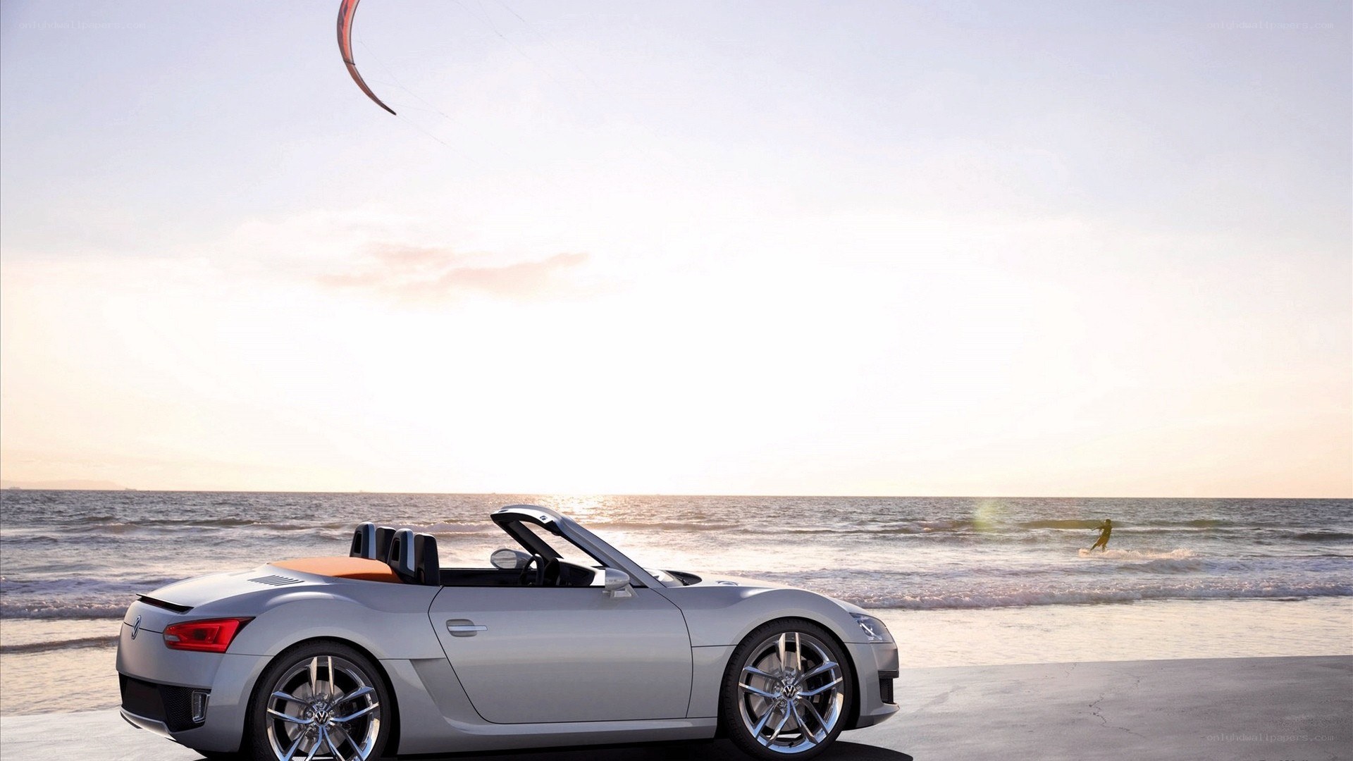 Silver convertible on beach at sunset