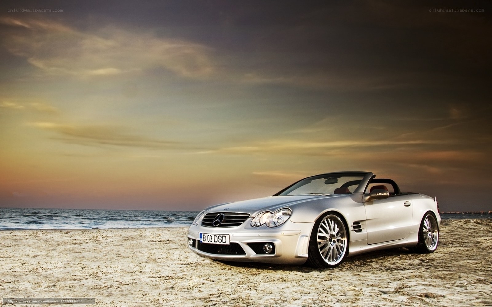 Silver convertible on beach at sunset