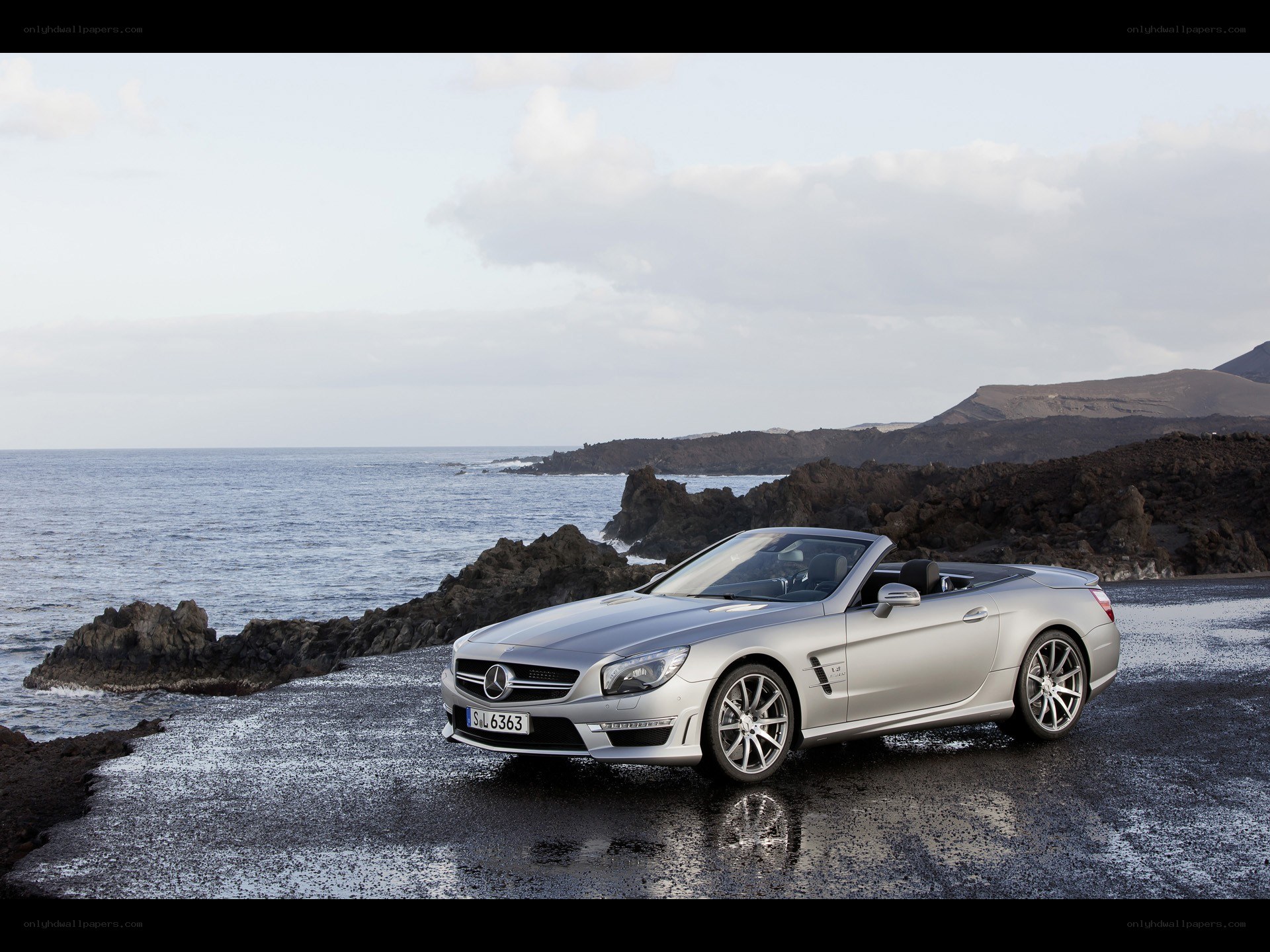 Silver convertible on rocky shore
