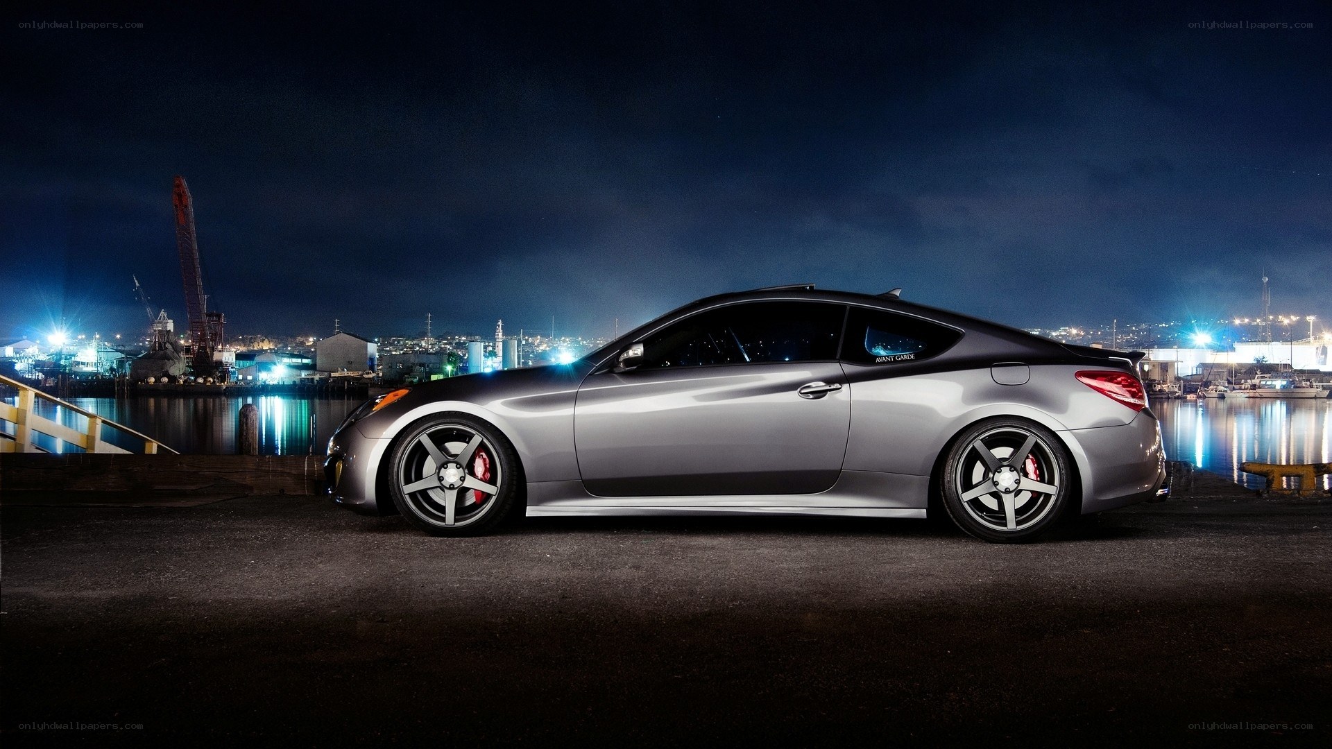 Silver coupe at night by the harbor