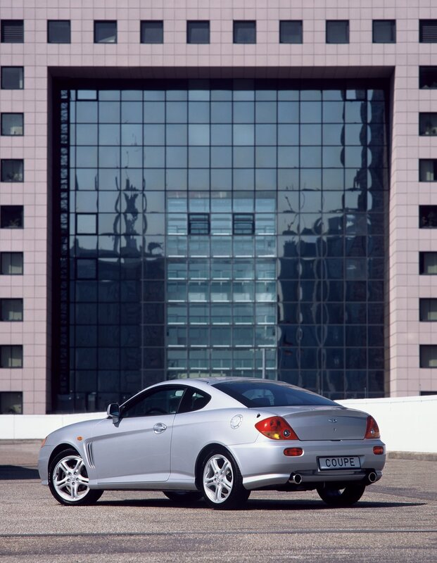 Silver coupe parked in front of building