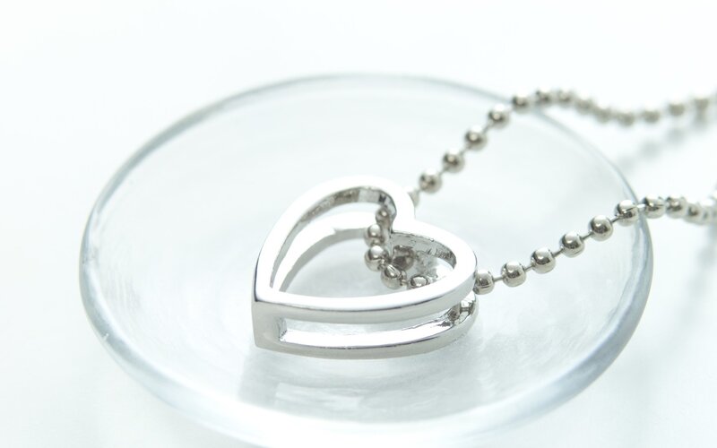silver heart necklace on glass