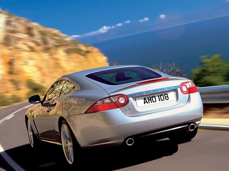 silver jaguar driving on coastal road