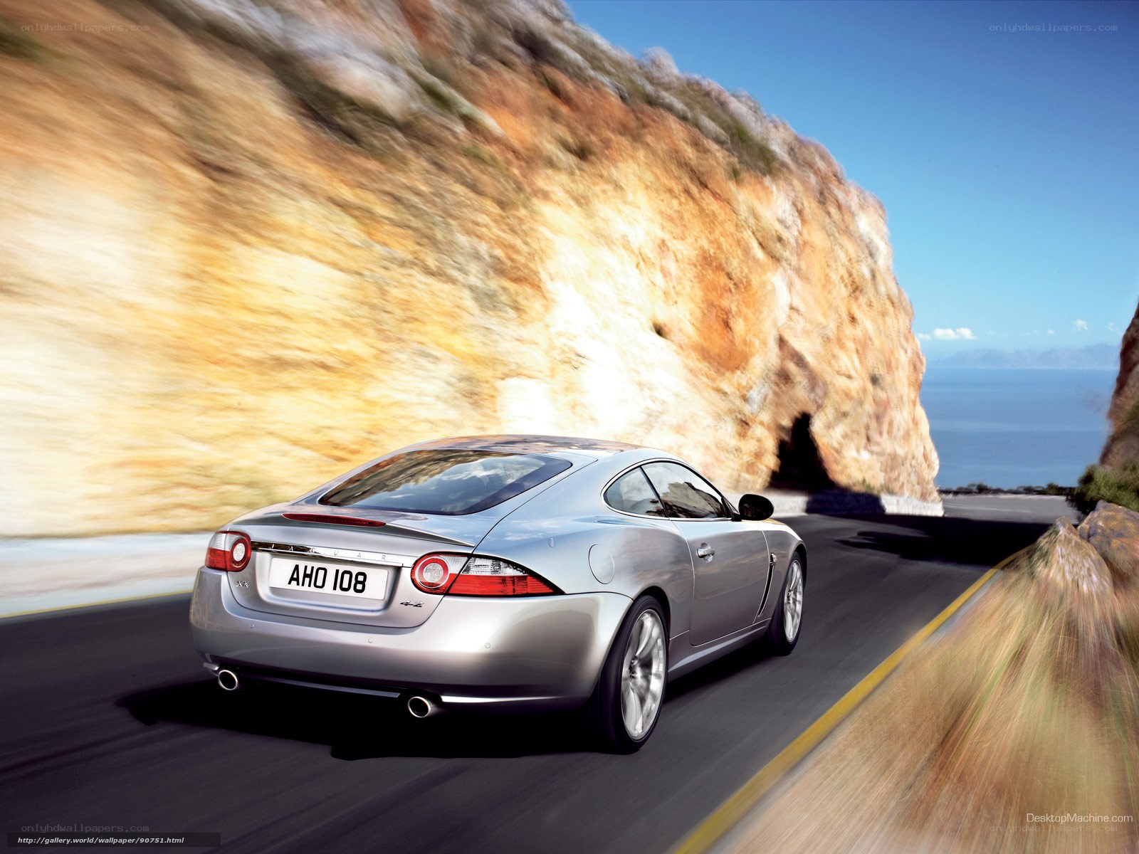 silver jaguar driving on coastal road