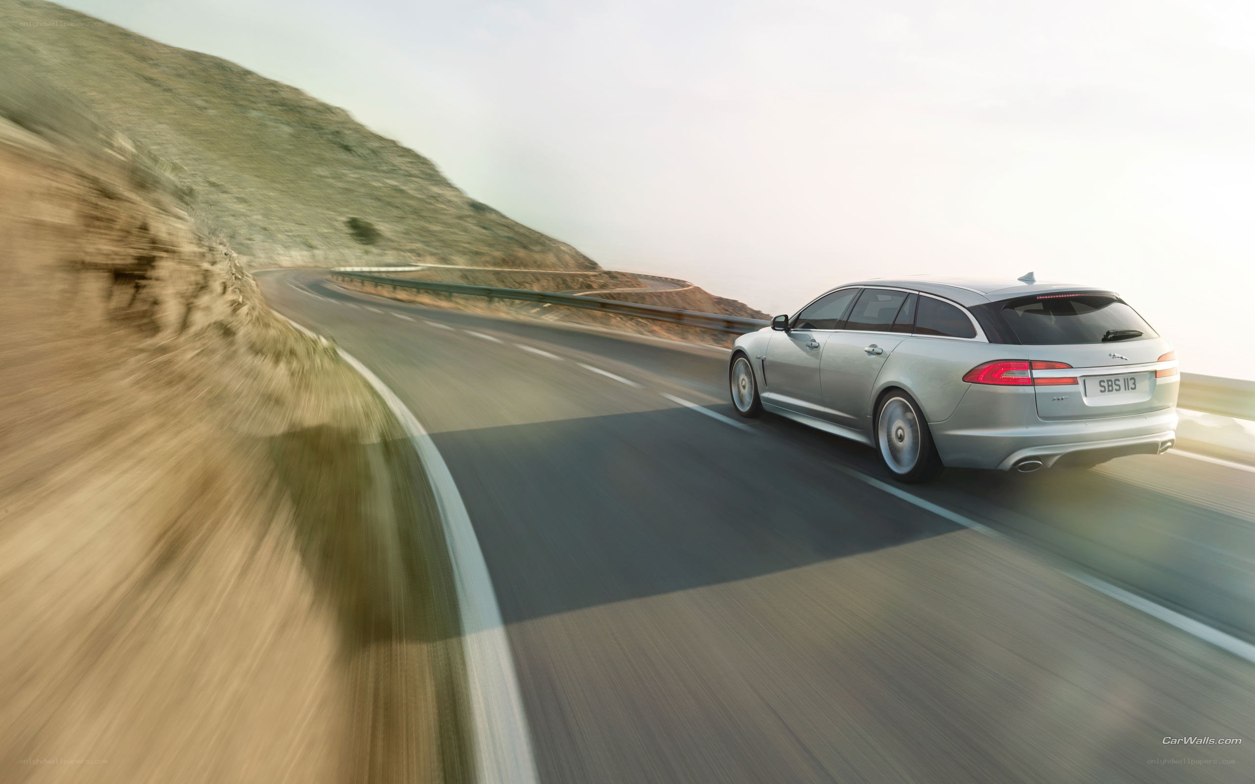 silver jaguar driving on winding road