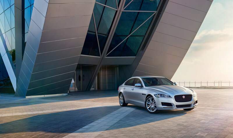 Silver Jaguar in front of modern building