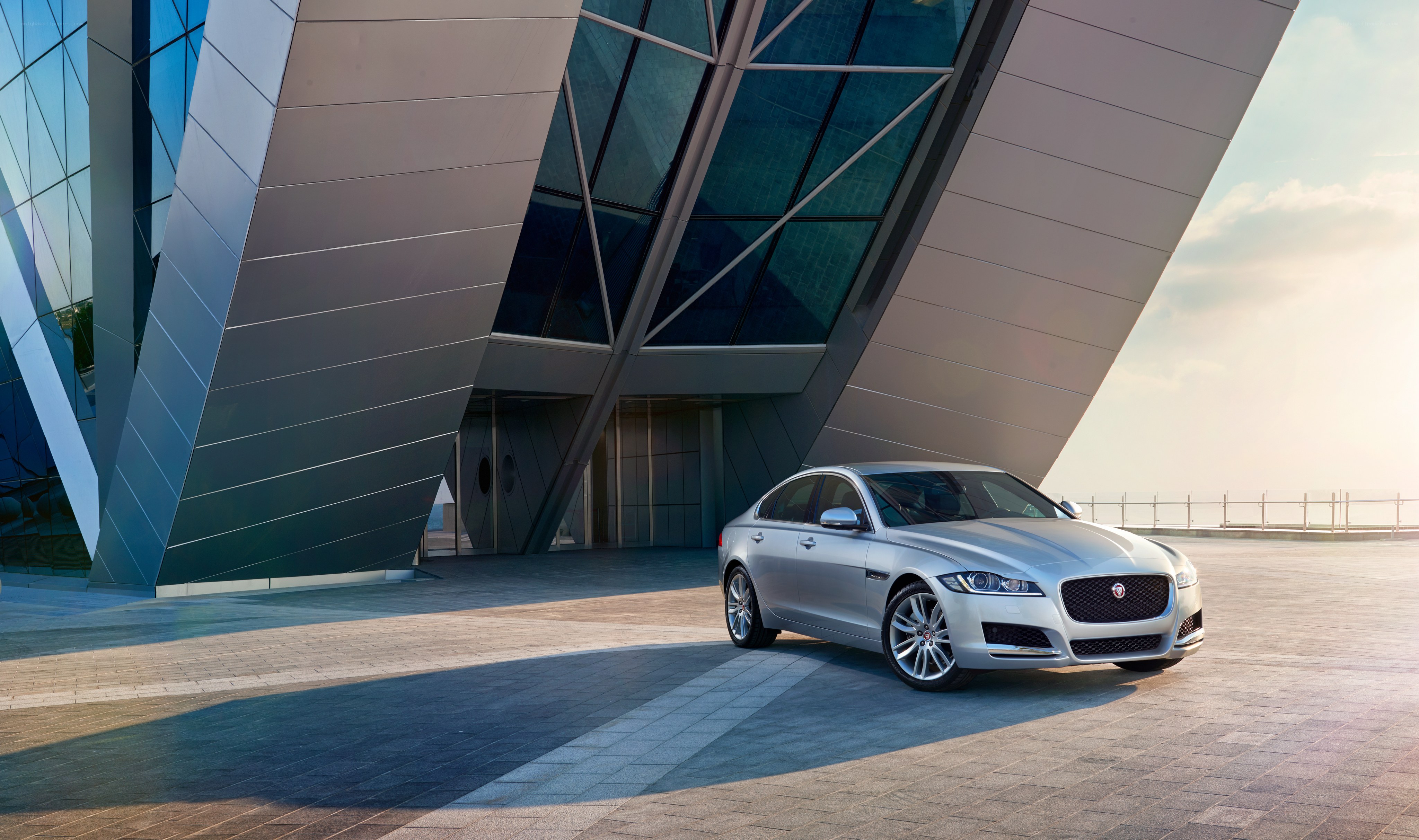 Silver Jaguar in front of modern building