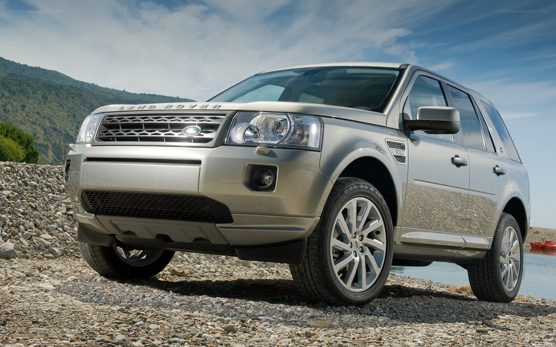 Silver Land Rover on a pebble beach